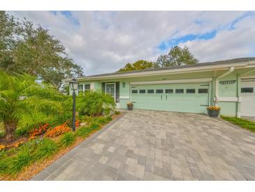 House exterior featuring a light green garage door, paved driveway, and well-manicured landscaping at 2510 Lambdin Dr, Sun City Center, FL 33573