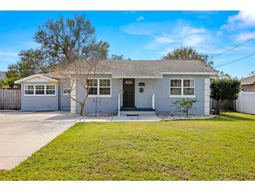 Charming Bungalow style home with gray exterior, landscaped lawn, and driveway at 4424 W Bay Villa Ave, Tampa, FL 33611