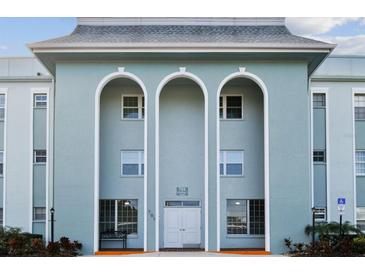 Building exterior featuring a light blue facade, three arched entryways, and landscaping at 701 Poinsettia Rd # 302, Belleair, FL 33756