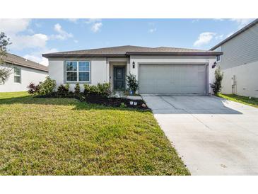 Curb appeal abounds in this charming one-story home featuring a gray garage door and well-manicured lawn at 9215 Royal River Cir, Parrish, FL 34219