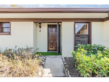 Inviting condo entry with brown door and landscaping at 1311 Powderpuff Dr # 4, Dunedin, FL 34698