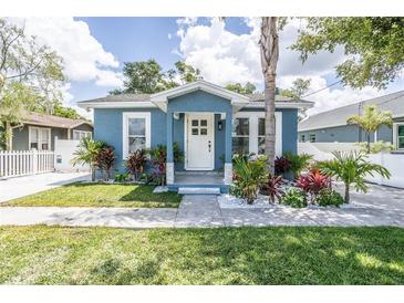 Charming bungalow with a freshly painted blue exterior, landscaping, and a white picket fence at 8907 N Boulevard, Tampa, FL 33604