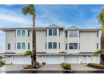 Three-unit building, light beige siding, attached garages, and landscaping at 9341 Blind Pass Rd, St Pete Beach, FL 33706