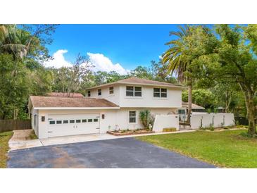 White two-story house with attached garage, landscaping, and a long driveway at 525 Appaloosa Rd, Tarpon Springs, FL 34688