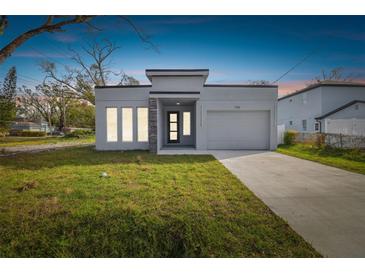Modern single-story home with gray exterior, stone accents, and attached garage at 7711 N Orleans Ave, Tampa, FL 33604