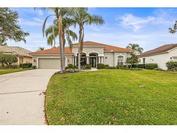 Single-story home with tile roof, palm trees, and a well-manicured lawn at 4339 Cheval Blvd, Lutz, FL 33558