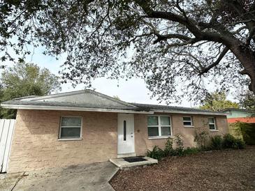 Tan house with white door, landscaping, and large tree in front at 6985 82Nd N Ave, Pinellas Park, FL 33781