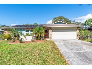 Ranch-style home with solar panels, landscaped yard, and attached garage at 8460 Parkwood Blvd, Seminole, FL 33777