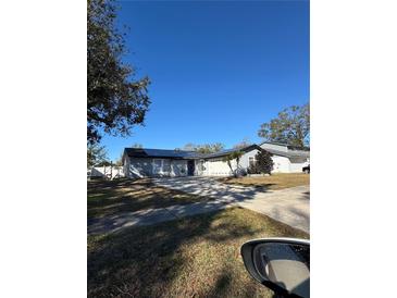 Ranch-style home with gray siding, solar panels, and a driveway at 15906 Country Farm Pl, Tampa, FL 33624