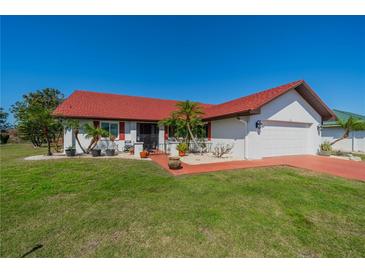 Charming single-story home featuring a red tile roof, white exterior, well-manicured lawn, and an attached two-car garage at 1723 Wolf Laurel Dr, Sun City Center, FL 33573