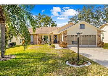 Brick ranch home with a two-car garage and landscaped lawn at 2249 Grandfather Mtn, Spring Hill, FL 34606