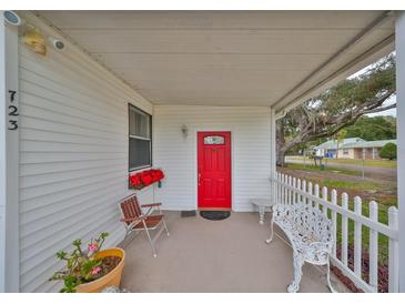 Inviting front porch with red door, white picket fence, and comfortable seating at 723 Ornelda Sw St, Ruskin, FL 33570