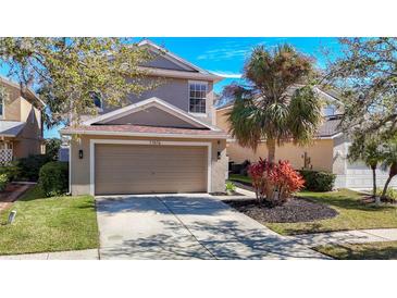 Two-story house with a tan exterior, two-car garage, and landscaped yard at 11616 Crest Creek Dr, Riverview, FL 33569