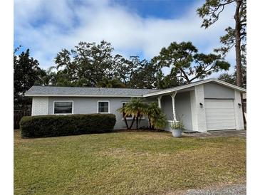 Gray house with white trim, nicely landscaped lawn, and attached garage at 12264 103Rd St, Largo, FL 33773