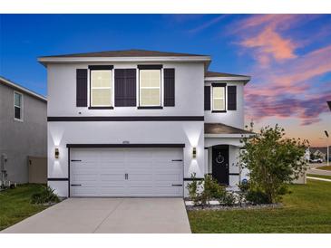 Two-story home with white and gray exterior, two-car garage, and landscaping at 16961 Oval Rum Dr, Wimauma, FL 33598