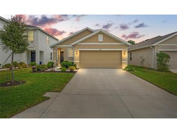 Tan two-story house with a two-car garage and landscaped lawn at 3304 Suncoast Plains Dr, Odessa, FL 33556