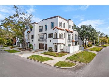 Three-story home with stucco exterior, two-car garage, and a landscaped yard at 418 S Albany Ave, Tampa, FL 33606