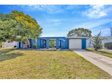 Ranch-style home with blue exterior, single car garage, and well-maintained lawn at 4308 Craftsbury Dr, New Port Richey, FL 34652