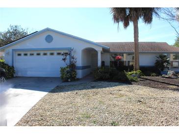 White house with blue accents, two-car garage, and landscaping at 5528 Berlin Dr, Port Richey, FL 34668