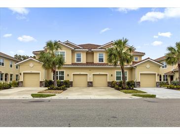 Tan three-story townhome with three garage doors and palm trees at 8332 Enclave Way # 101, Sarasota, FL 34243