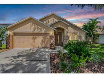 Tan one-story house with a two-car garage and landscaped front yard at 122 Orange Bud Way, Plant City, FL 33563