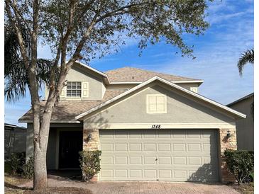 Two-story house with a neutral exterior, two-car garage, and landscaping at 1348 Impatiens Ct, Trinity, FL 34655