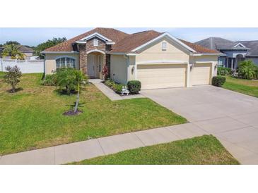 Tan house with brown roof, two-car garage, and landscaped yard at 14638 Strathglass Dr, Hudson, FL 34667