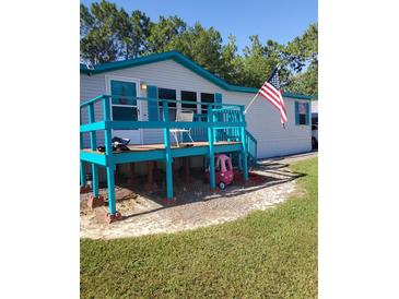 Mobile home with large deck, American flag, and spacious yard at 6274 Boatwrite Rd, Spring Hill, FL 34609