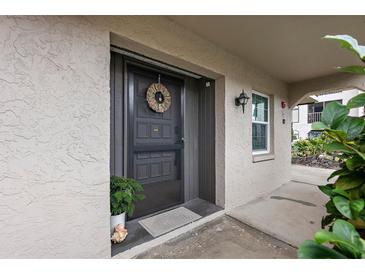 Inviting condo entryway with a wreath and potted plants at 8703 Bardmoor Blvd # 106, Seminole, FL 33777