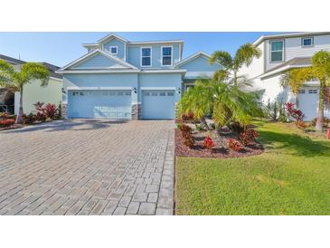 Two-story light blue house with a three-car garage and landscaped front yard at 935 Signet Dr, Apollo Beach, FL 33572