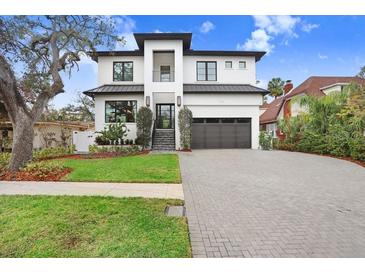 Two-story modern home with white brick exterior, black metal roof, and landscaped yard at 2623 S Parkview St, Tampa, FL 33629