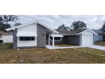 Updated house exterior boasts gray stone, white accents, and a paved driveway at 4024 Jib Sail Ct, New Port Richey, FL 34652