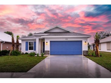 Newly constructed home with a blue garage door and landscaping at 425 Rose Apple Cir, Port Charlotte, FL 33954