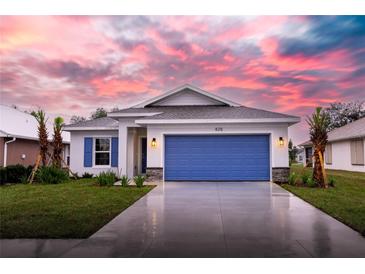 One-story home with blue garage door and landscaped yard; sunset in the background at 425 Rose Apple Cir, Port Charlotte, FL 33954