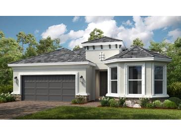 One-story home with gray roof, two-car garage, and landscaping at 5208 Savino Cir, Palmetto, FL 34221