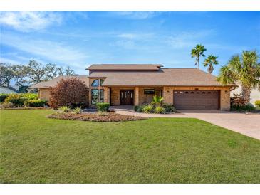 Brick house with brown roof, landscaping, and a large yard at 6151 Silver Oaks Dr, Zephyrhills, FL 33542