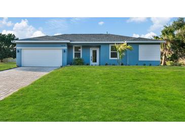 Newly constructed home with light blue exterior, white garage door, and a landscaped lawn at 18400 Tulane Ave, Port Charlotte, FL 33954