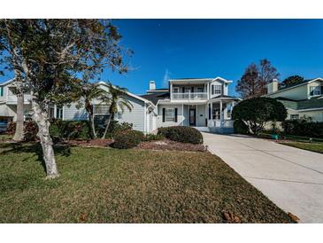 Charming two-story home features a lovely front porch and balcony, landscaped yard and long driveway at 2930 Swan Cir, Dunedin, FL 34698