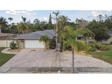 Single-story home with a large driveway and lush landscaping at 775 Rolling Hills Dr, Palm Harbor, FL 34683