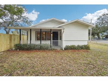 White house with a covered porch, fenced yard, and well-manicured landscaping at 1424 E Bougainvillea Ave, Tampa, FL 33612