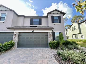 Two-story townhome with a two-car garage and landscaped front yard at 5110 San Martino Dr, Wesley Chapel, FL 33543