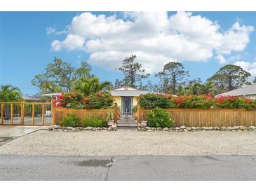 Cute yellow house with attractive landscaping and a wood fence at 5780 Elton Rd, Venice, FL 34293