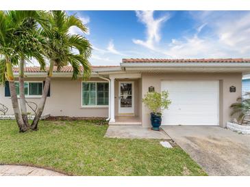 Tan house with a white garage door and palm trees in front at 809 Mandalay Ave, Clearwater Beach, FL 33767