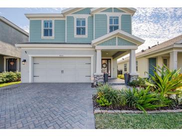 Two-story house with light teal siding, gray garage door, and landscaped front yard at 4456 Tubular Run, Land O Lakes, FL 34638