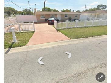 Tan single-story house with white picket fence and driveway at 6502 W Clifton St, Tampa, FL 33634