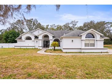 White house with gray roof, arched entryway, and landscaped lawn at 8535 Delaware Dr, Weeki Wachee, FL 34607