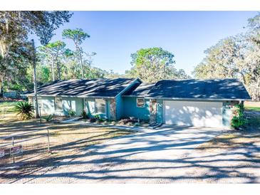 Ranch style home with a two car garage and mature landscaping at 8615 Greenfield Ln, Zephyrhills, FL 33541