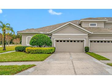 Tan two-story home with attached garage and manicured landscaping at 16130 Craigend Pl, Odessa, FL 33556