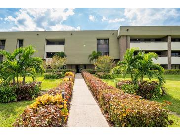 Building exterior with landscaped walkway and lush tropical plants at 36750 Us Highway 19 N # 04221, Palm Harbor, FL 34684