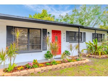 Updated ranch home with red door, landscaping, and modern exterior at 4702 W Bay Ave, Tampa, FL 33616